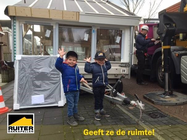 Kinderen naast prefab dakkapel op een aanhanger.